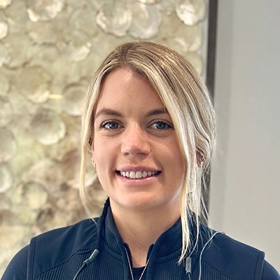 Dentist Kaeleigh Morton Smiling In Front Of Art Piece